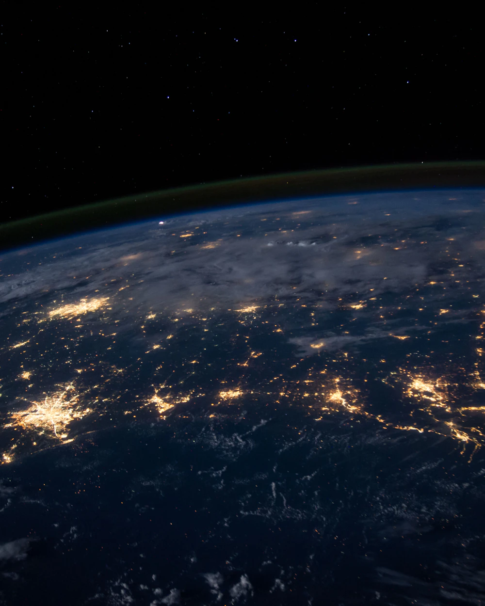 Earth at night from space, city lights glowing across continents