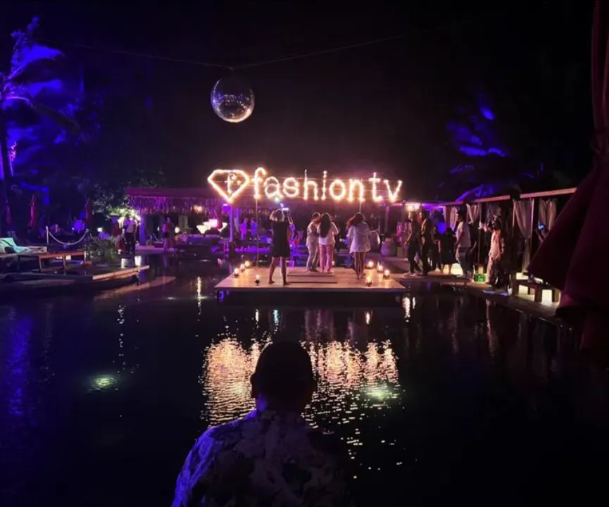 Night pool party — glowing fashiontv heart sign over the water