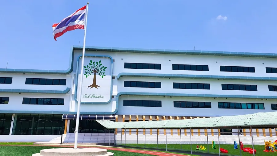Oak Meadow campus building with Thai flag and school logo on the facade