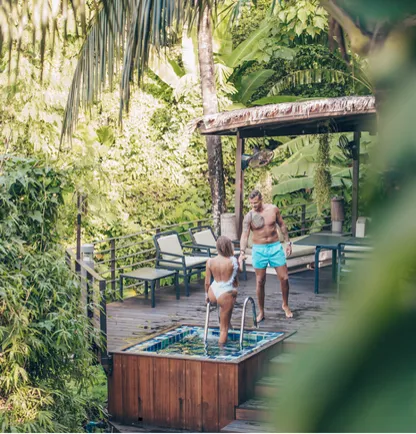 Guests at the outdoor cedar hot tub surrounded by tropical greenery